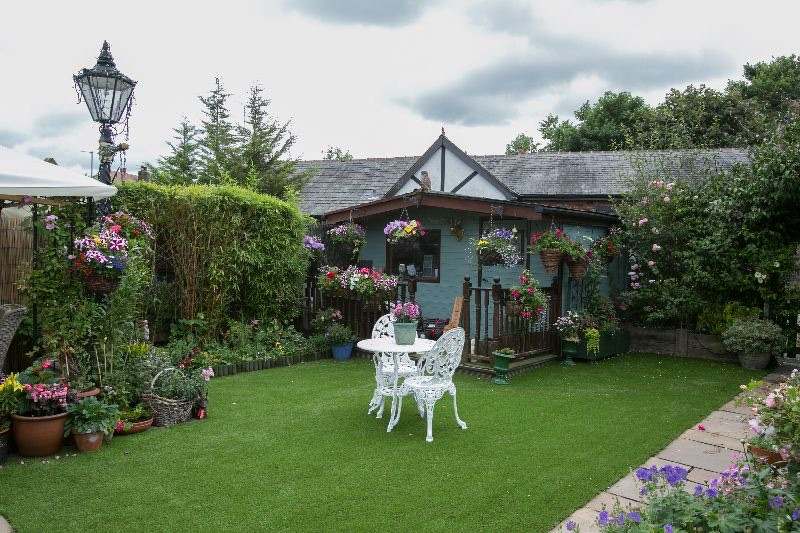 An artificial lawn in front of a summerhouse with hanging baskets